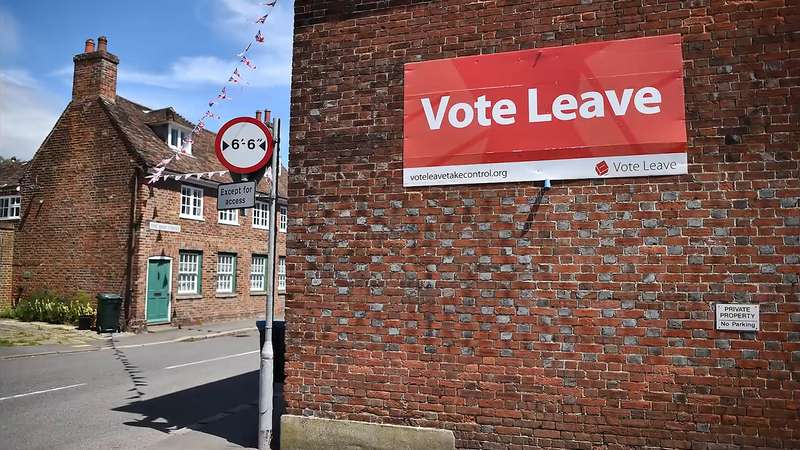 A sign aside a brick building, indicating "Vote Leave."