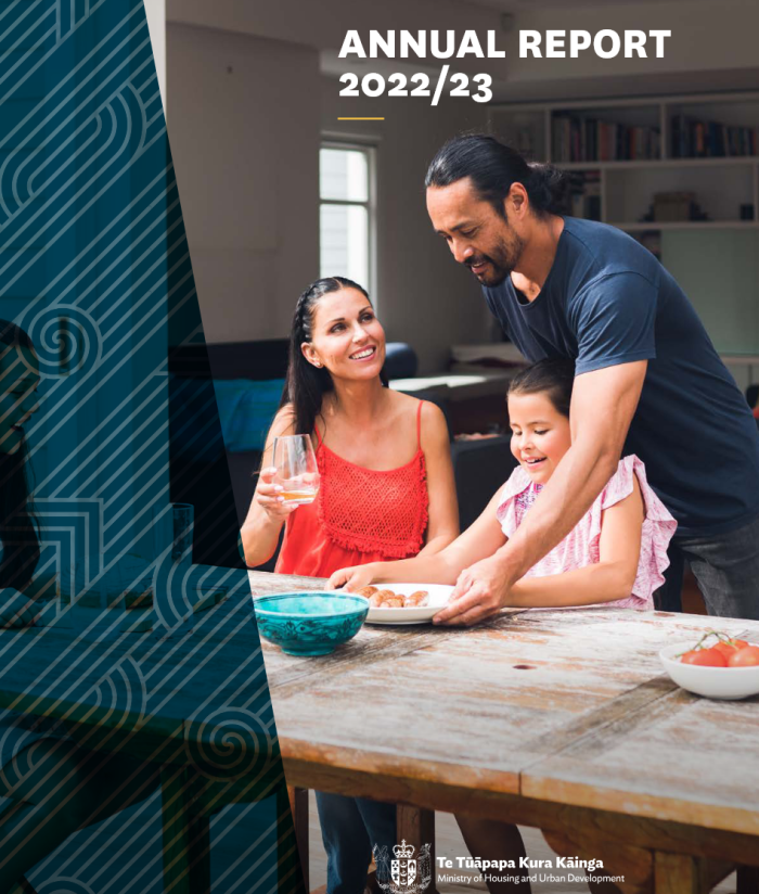 Whānau gathered around a table sharing kai, featuring a couple and their child, symbolizing community, care, and connection — cover image of the HUD Annual Report 2022/23.
